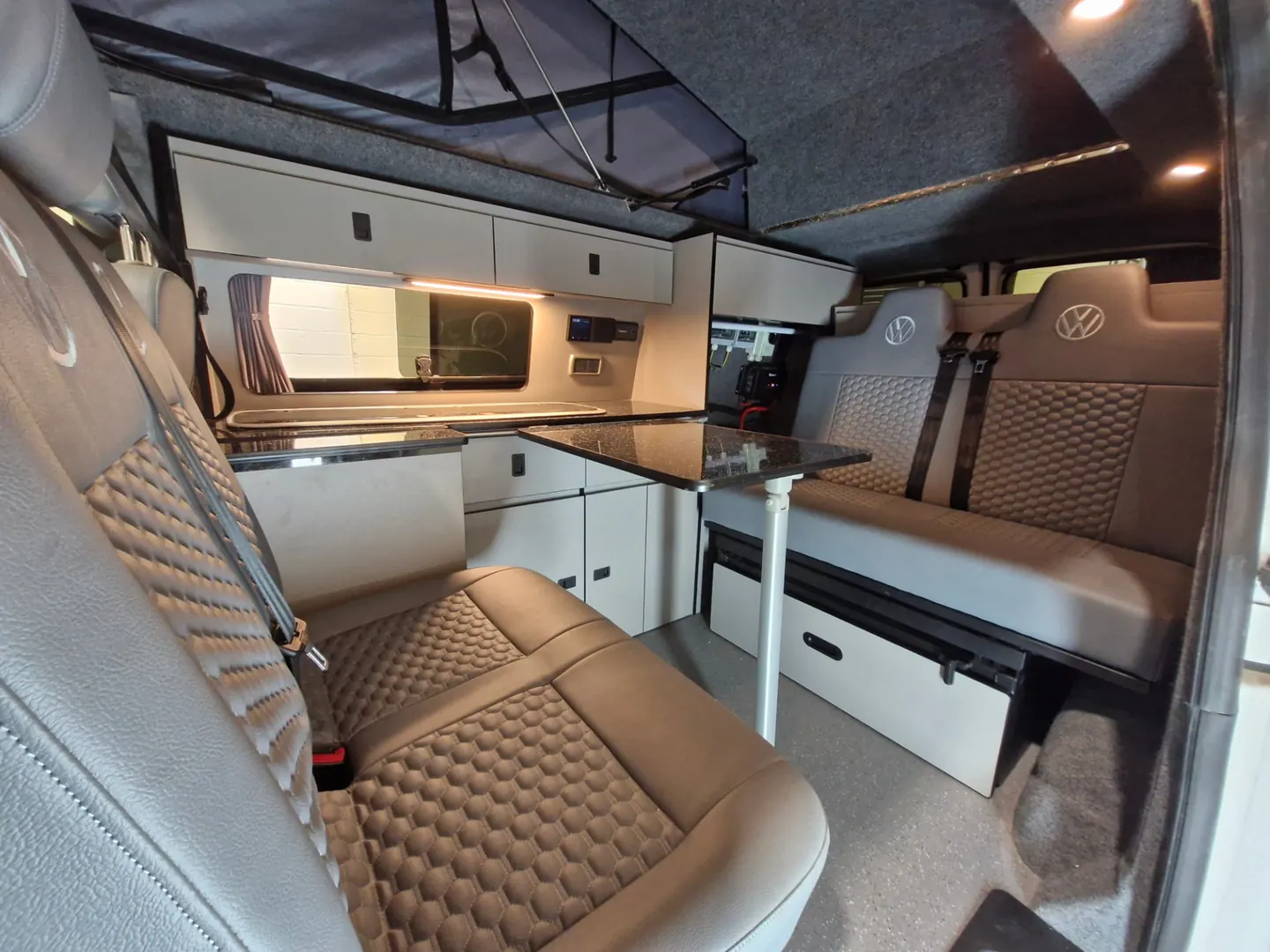 Full campervan interior with fitted kitchen, rock and roll bed, pop-top roof and trimmed seating