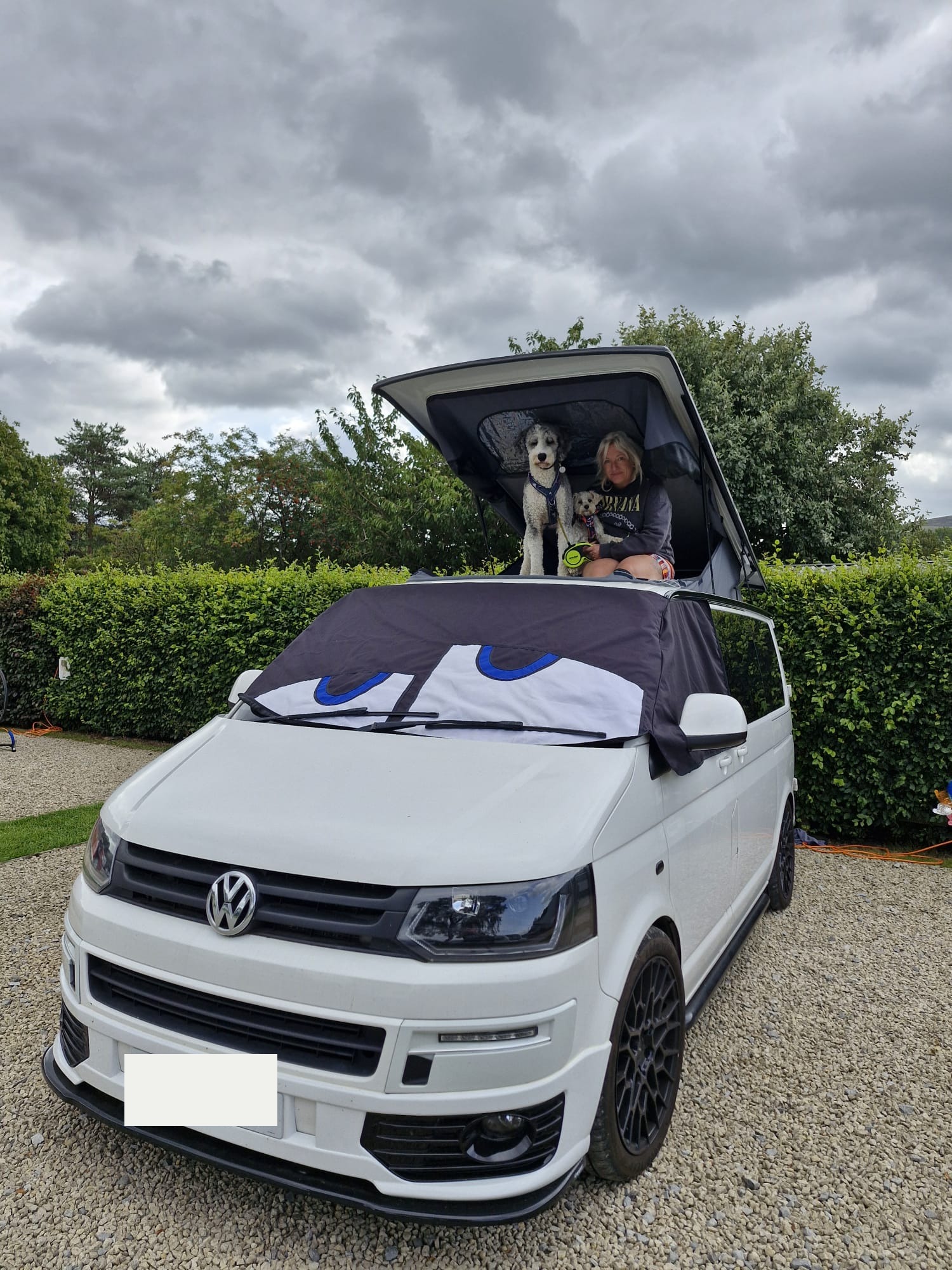 White Volkswagen Transporter campervan converted by Potteries Camper Co with its pop-top roof raised and the upper bed in use